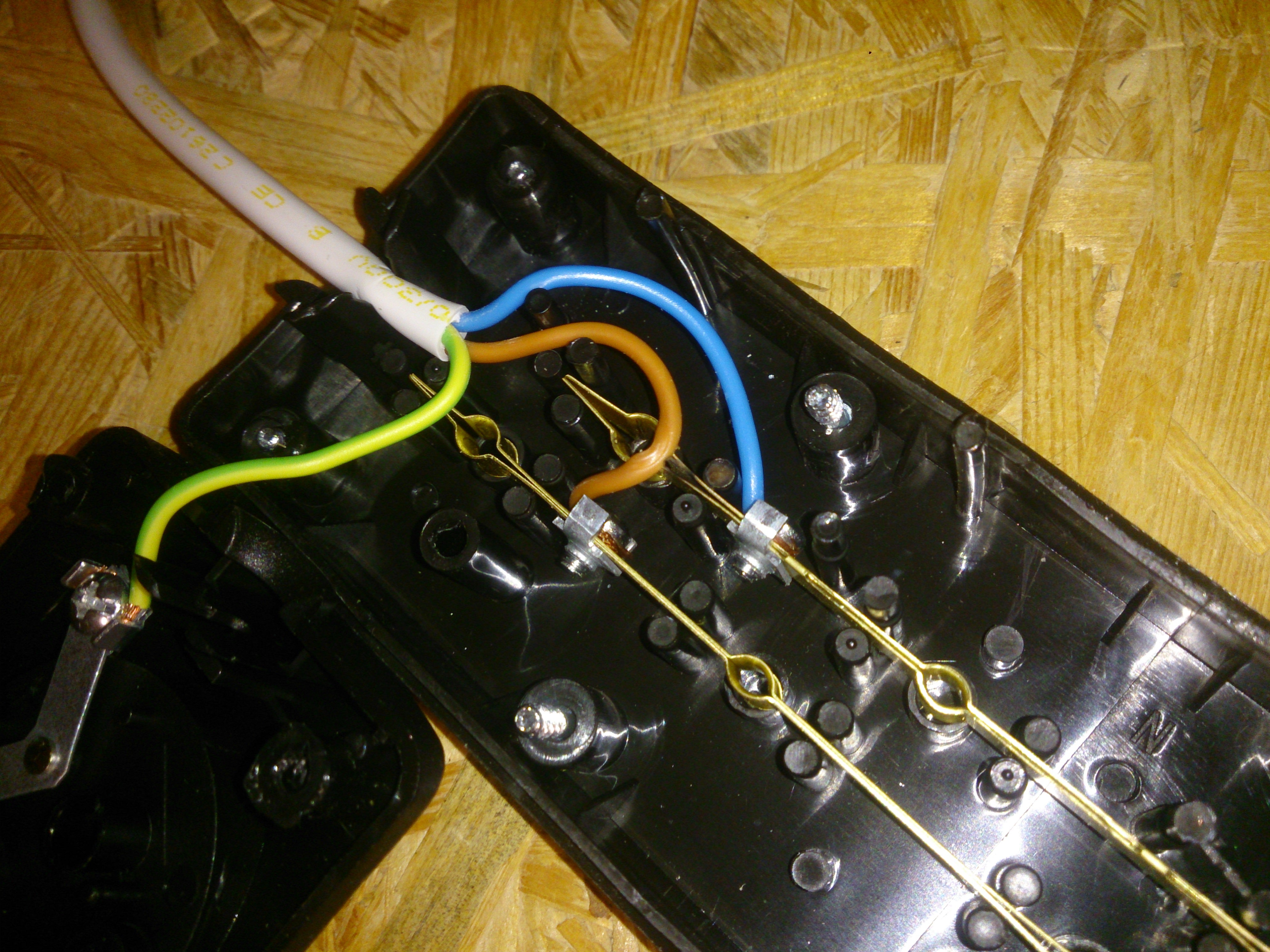 extension cord socket bit, open, the brown wire is conspicuously streched on top of the distribution bar for the blue wire; darkening around this is visible